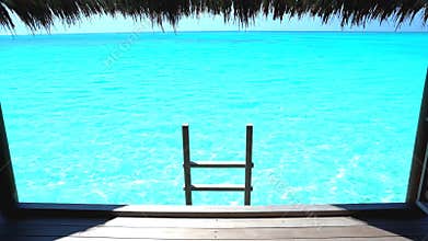 Serene view from an overwater bungalow deck with a ladder leading into calm turquoise tropical water