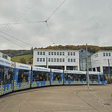 Modern blue tram with IKEA advertising turning in front of contemporary buildings and autumn hills in Bern, Switzerland