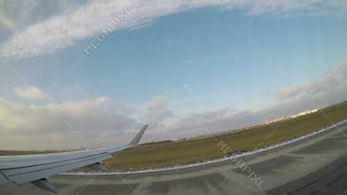 Airplane wing gliding through the sky, capturing the gradual descent towards the runway, showcasing the expansive landscape and
