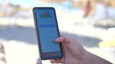 A travelers hands on a beach review the description and terms for downloading an offline map through a mobile