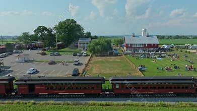 Train Travels Through Farm Festival in Sunny Countryside With Families Enjoying Activities