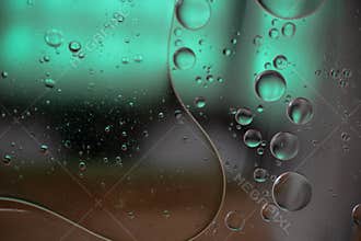 Oil slicks floating on the surface of the water with a gradient green background with selective focus.