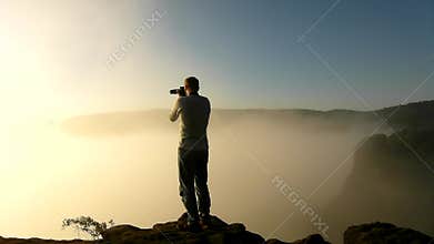 Photograph in action within magnificent misty sunrise in a beautiful mountain of sandstone rocky peaks.