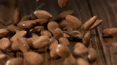 Almonds fall onto a wooden surface in a kitchen during the day with natural light shining through the window