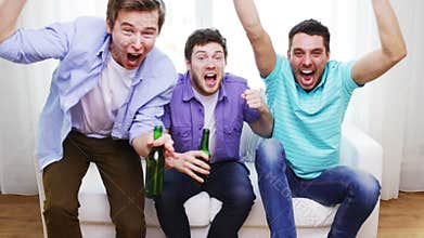 Happy male friends with beer watching tv at home