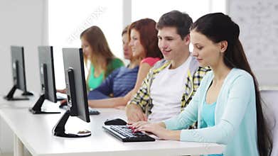 Smiling students working with computers at school