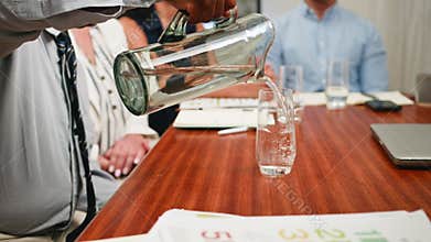 Businessman Pouring Fresh Water into a Glass During a Professional Boardroom Meeting