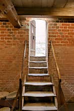 Stairs leading to a wooden door illuminated by natural light in a brick building