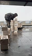 A stove fitter builds a chimney on the roof of a building. Construction of a heating stove. Vertical video