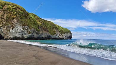 A solitary big waves of the atlantic ocean coming in to the sandy volcanic beach of Santa Barbara, Sao Miguel, Azores, Portugal