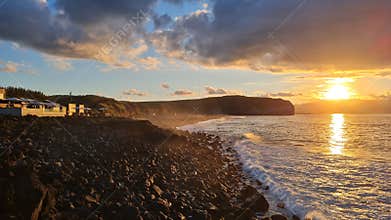 Golden sunset reflects over the atlantic ocean at the volcanic beach of Santa Barbara, Ribeira Grande, Sao Miguel, Azores