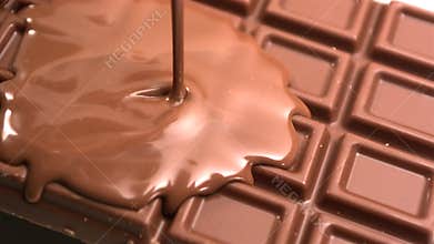 Melted chocolate being poured over a bar of chocolate