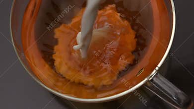 Milk pouring into cup of tea
