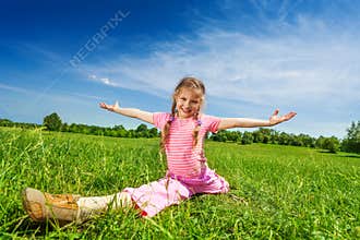 Girl makes leg-split on grass with arms apart