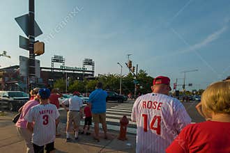 A group of people are standing on a street, some wearing Philadelphia Phillies jerseys