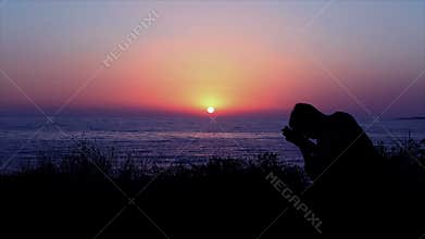 Man Praying by the Sea at Sunset