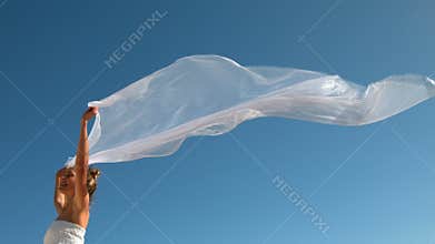 Carefree blonde holding scarf up blowing in the wind