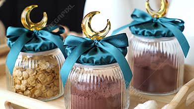 Three Glass Jars with Teal Bows and Crescent Moon Charms Displayed on a Wooden Tray