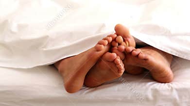 Couples feet wiggling under the duvet