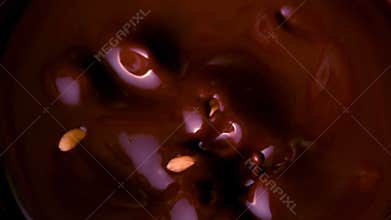 Peanuts falling in melted chocolate