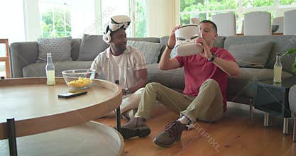 Diverse male friends putting on VR headsets at home gaming for fun then sharing lemonade toast