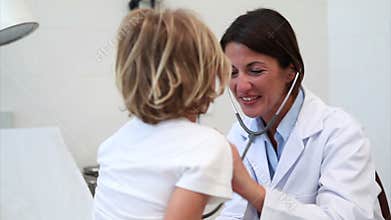 Smiling doctor auscultating a child