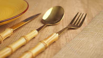Eating utensils on a wooden table with a glass