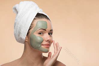 Spa girl with a towel on her head applying facial