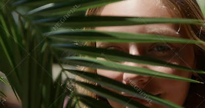 Woman's Face Peeking and Smiling Through Palm Leaves