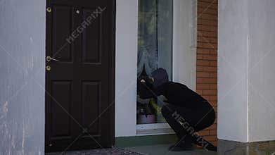 There is an intruder currently attempting a breakin at a residential front door area