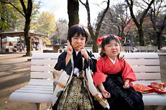 Kawagoe, Japan- 1 December 2019 : Smiling Japanese children in traditional kimono sitting on a bench, celebrating cultural