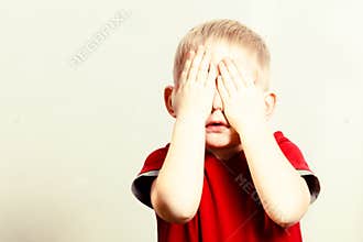 Happy childhood. Blond boy child kid covering face with hands