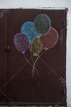 Colorful balloons drawn with chalk on a brown metal door