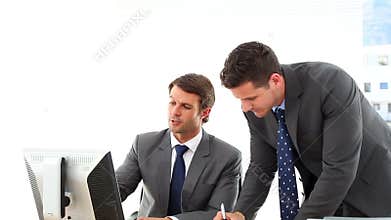 Businessmen looking at computer screen talking