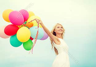 Smiling woman with colorful balloons outside