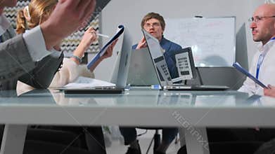 Business team discussing strategy with laptops and documents during meeting