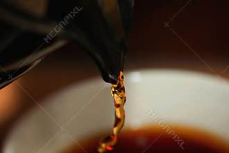 Close-up photo of a caraffe spout pouring coffee into a cup