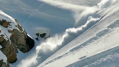 Snowy mountain landscape with blowing snow and visible ski tracks on a bright winter day scene