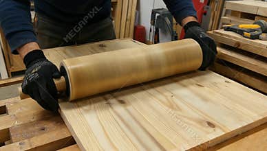 Woodworker smooths a wooden panel with a roller in a workshop for woodworking projects