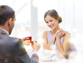 Excited young woman looking at boyfriend with ring