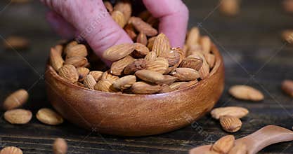 yellow brown whole nuts of unroasted almonds with a wooden spoon