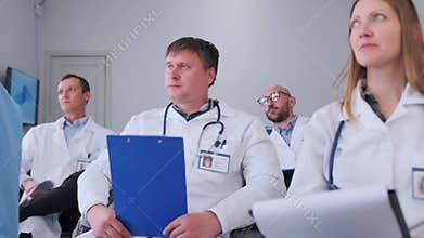 Doctors taking notes and asking questions during seminar