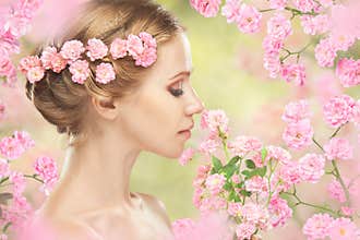 Face of young beautiful woman with pink flowers in her hair