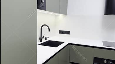 Modern olive green kitchen interior with black sink and faucet