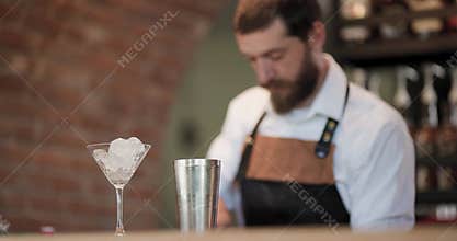 Barman prepares a cocktail with ice and shaker at