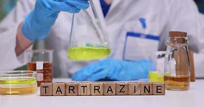 Laboratory worker slowly rotates glass beaker to mix solution