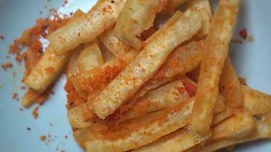 A macro, top-down shot of golden-brown, crispy cassava or vegetable chips piled high on a white plate