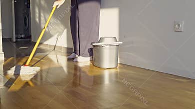 Person Mopping a Shiny Wooden Floor in a Sunlit Home, Performing a Daily Household Chore