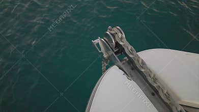 Anchor chain lowering from yacht bow into deep turquoise sea water