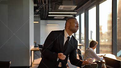Boss Businessman dancing by window in the office during sunset